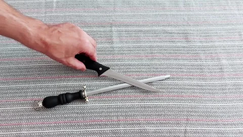 Sharpening a Kitchen Knife with Honing Rod on Textured Surface Vídeo Stock 314252311