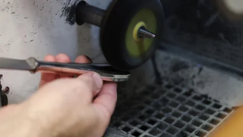 Sharpening a knife using a grinding wheel in a workshop Stock Footage 322519889