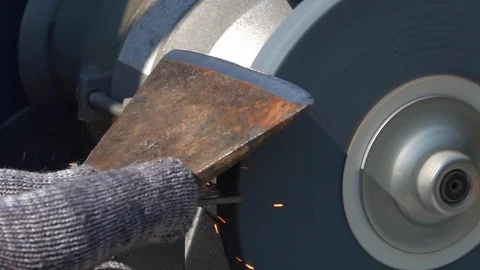 Sharpening of old ax with unbalanced grinding machine in slow motion close up. Stock Footage 98677913