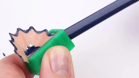 Sharpening a pencil with a green sharpener. Close-up of a hand holding a blue Stock Footage 304065129