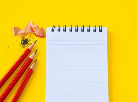 Sharpening a red pencil sharpener and the note book On yellow background. Stock Photos