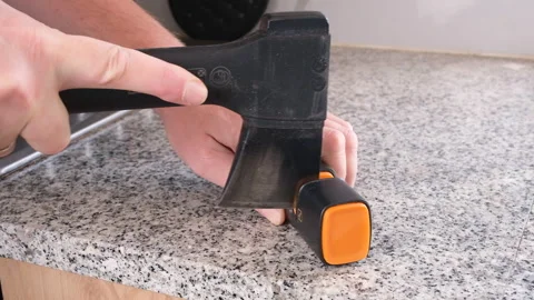 Sharpening a small hatchet with a manual sharpener 스톡 동영상 338012989