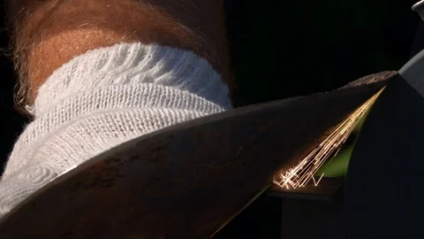 Sharpening of soiled and rusty garden tool with grinding machine in slow motion Stock Footage 98676713
