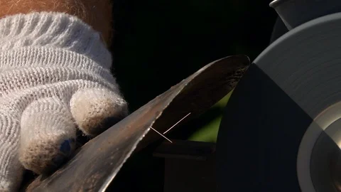 Sharpening of soiled and rusty garden tool with grinding machine close up. Stock Footage 98676754