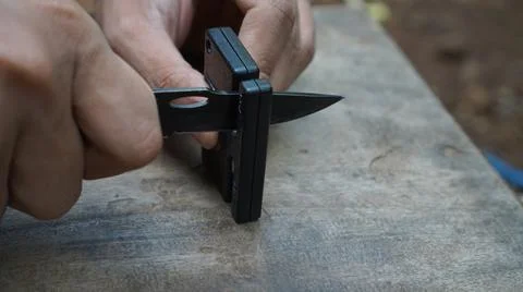 Sharpening survival knife on a simple sharpener 스톡 사진