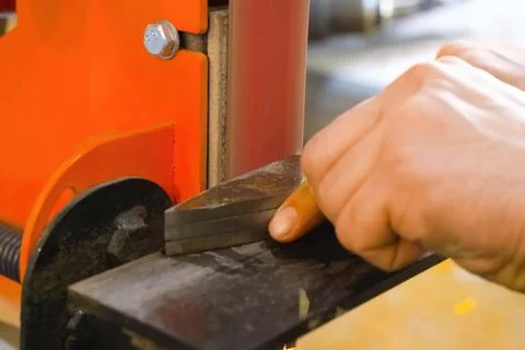 Sharpening throwing knife on a grinding machine. Stock Photos