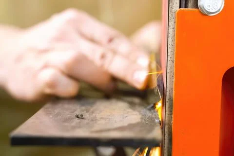 Sharpening throwing knife on a grinding machine. Stock Photos