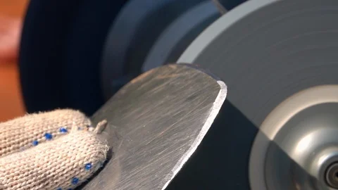Sharpening of worn garden tool with grinding machine in slow motion close up. Stock Footage 98676328