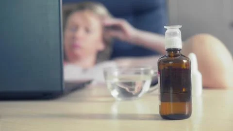 In sharpness medications stand on the table where blurred woman uses laptop 库存插图