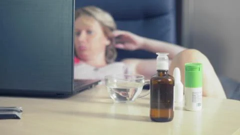 In sharpness medications stand on the table where blurred woman uses laptop 库存插图