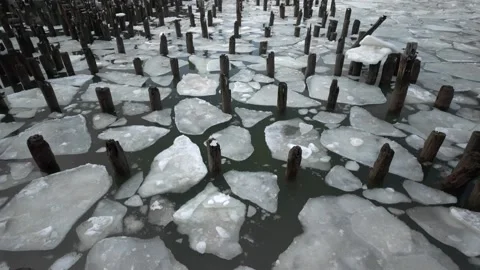 Shattered ice floating on the water with broken wood posts at old pier - 4K Stock Footage 328370016