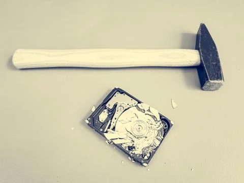 Shattered platter in computer hard drive disk and a hammer. Stock Photos