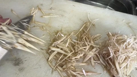 Shaved burdock root strips piling up as Japanese chef whittles gobo with knife Stock Footage 342766789