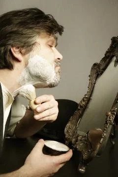 Shaving beard at home on kitchen table in prewar style - creme applying Stock Photos