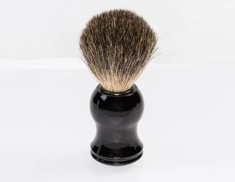 Shaving brush stands on a light surface, close-up Stock Photos