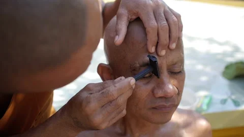 Shaving eyebrows to new monk in temple. Close up. Ordaining ceremony be a monk Stock Footage 161783574
