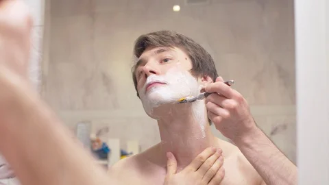 Shaving man reflected in the mirror Stock Footage 128890711