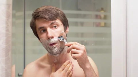 Shaving man reflected in the mirror Stock Footage 128916443