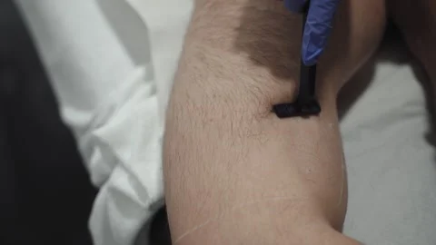 Shaving man's arm with black razor - close up Stock Footage 263739705