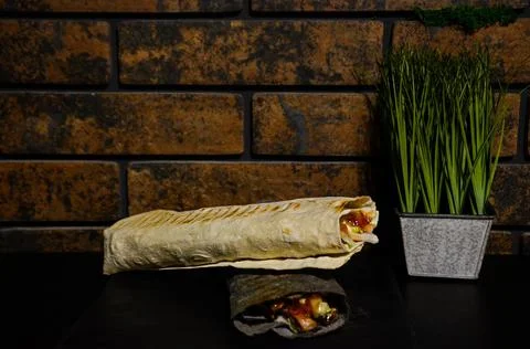Shawarma on a background of a brick wall and green space Foto stock