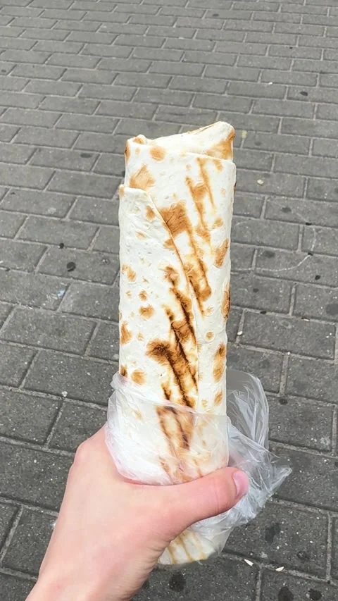 Shawarma in a grilled pita bread held in hands on the street Stock-Footage 336542436
