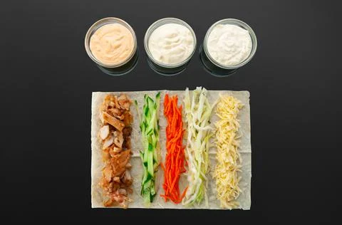 Shawarma ingredients. On a thin flat cake: grilled meat, cucumber, carrots, c Stock Photos