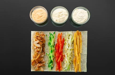 Shawarma ingredients. On a thin flat cake: grilled meat, cucumber, tomatoes,  Foto stock
