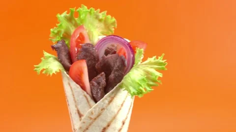 Shawarma moves on an orange background. 库存影片 143767457