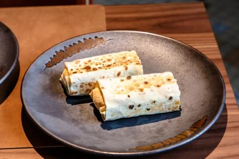 The Shawarma is wrapped in pita bread two piece lies on a plate Stock Photos