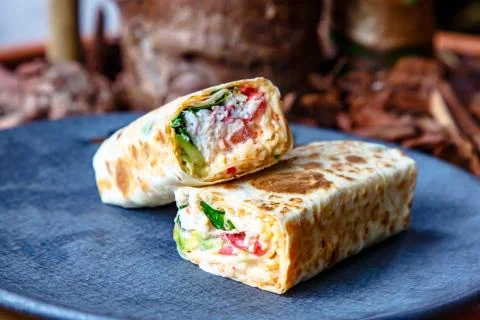 The Shawarma is wrapped in pita bread two piece lies on a plate Stock Photos