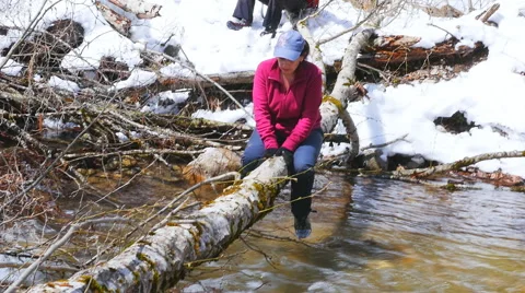 She barely crawling on fallen tree trunk over the river Stock Footage 50768293