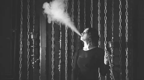 She blows smoke on a background of chains, black and white Stock Footage 68582246