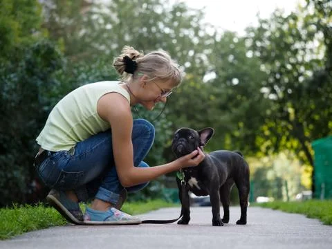 She communicates with the dog while walking. Street of the city, summer. Fren Stock Photos