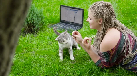 She feeds the cat outdoors. Work behind the laptop. Stock Footage 67836348