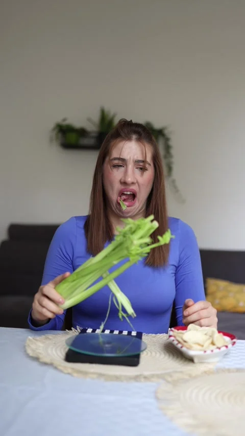 She forces herself to eat celery instead of chips Stock Footage 339855125