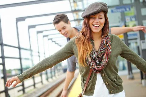 She has a child like spirirt. A smiling couple balancing along the railway of a Stock Photos
