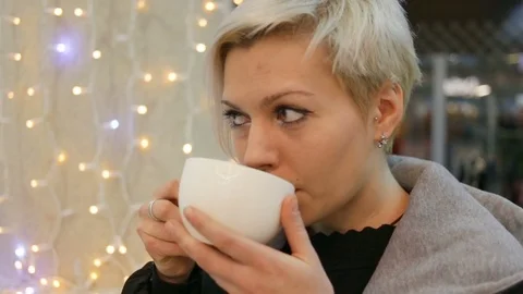 She has a wistful look, she drinks black coffee in small SIPS. Indoors, real tim Stock Footage 85193957