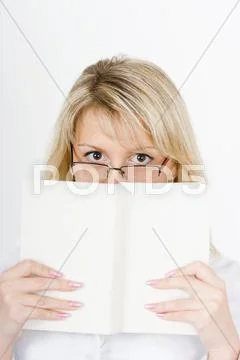She hides behind a book Stock Photos