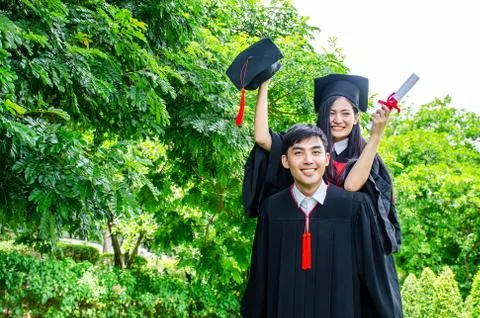 She is hugging him from the back is smiling and holding hat with the park Stock Photos