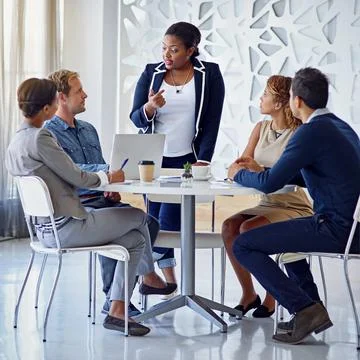 She leads by example. a group of colleagues working together in an office. Stock Photos