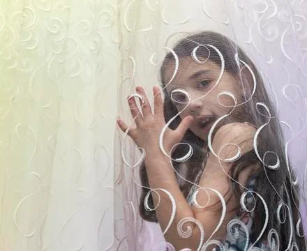 She looking at the camera behind the curtain Stock Photos