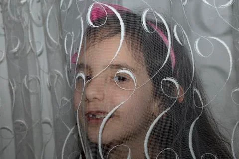 She looking at the camera behind the curtain Stock Photos
