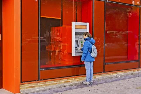 She is looking at the machine and putting money into it Stock Photos