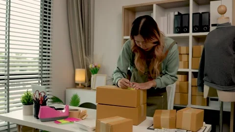She is packing clothes into the box, preparation of product that she sell to wai Stock Footage 296745265