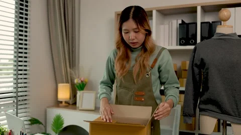 She is packing clothes into the box, preparation of product that she sell to wai Stock Footage 296745953