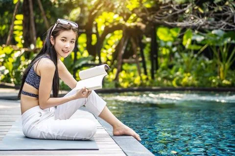 She reading book while relaxing near swimming pool Stock Photos