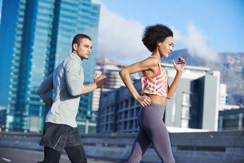 She sets a great pace. two friends jogging together through the city streets. Stock Photos