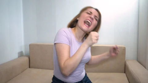 She sings, makes dance moves with his hands, sitting on the couch Stock-Footage 128165665