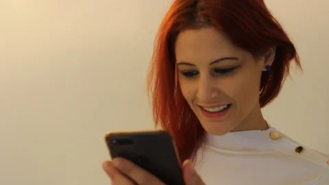 She is smiling  while uses the smartphone. Stock Footage 104819613