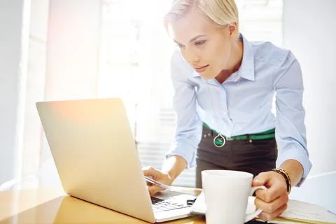 She spotted something interesting. a young businesswoman using a laptop at her Stock Photos